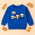 Blue kids sweatshirt with three cartoon pandas and a speech bubble saying HELLO, surrounded by wooden toys