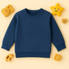 Zinc blue knitted pattern children's sweatshirt with ribbed cuffs on cream background with wooden toys