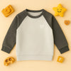 Grey and off-white raglan sweatshirt for kids with playful wooden toys on beige background