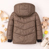 Brown kids puffer jacket with hood, black cuffs, displayed flat with toys and white shoes around