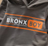 Close-up of gray hoodie with orange and white Bronx Boy logo and stripe design